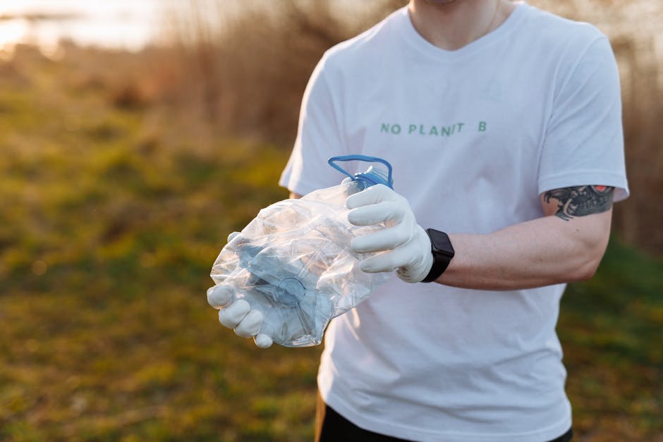 An overflowing collection of mixed waste, including cardboard boxes, plastic bags, paper debris, and discarded packaging, is piled around a large grey bin with a blue lid labeled for paper and cardboa